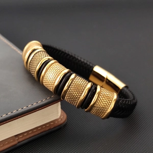 Detail of men's multi-layer black braided leather bracelet with golden textured metal links