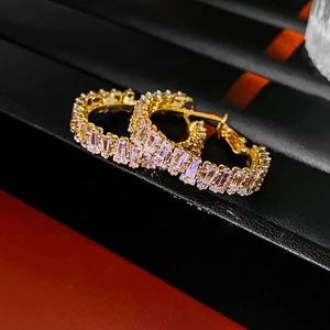 Macro shot of gold heart-shaped hoop earrings with lavender rectangular zircon stones