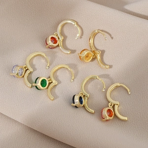 Set of six colorful zircon drop earrings with gold hoop pendants on beige fabric