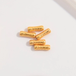 Macro view of gold S925 silver cylinder beads with irregular hammered bamboo texture