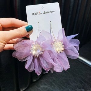 Dettaglio di orecchini a fiore in rete viola fatti a mano con perle di cristallo e ganci d'oro
