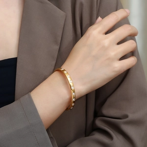 Detail of gold titanium bracelet with clear rhinestones on female wrist in office suit