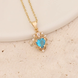Detail of golden heart necklace with ice blue gemstone and vintage filigree accents
