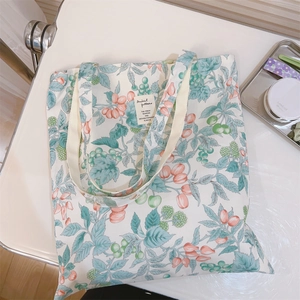 Close-up of floral cotton tote bag with green berry print and woven logo patch