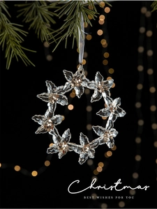 Macro detail of acrylic flower Christmas ornament with gold glitter and warm bokeh lights
