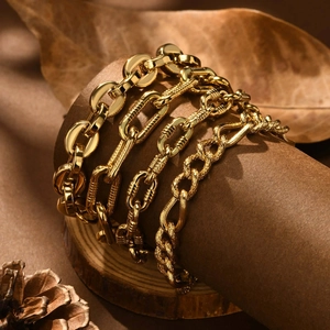 Set of four gold stainless steel textured chain bracelets on a rustic vintage display