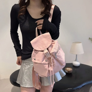 Detailed side view of a stylish pink nylon backpack worn by a model in a modern room