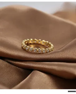 Macro shot of gold-plated eternity ring with bezel-set cubic zirconia on silk cloth