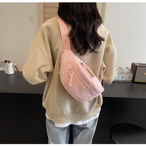 Detailed view of soft pink plush waist bag with adjustable strap worn by a female model