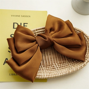 Detail of elegant caramel satin multi-layer bow hair clip on a woven background
