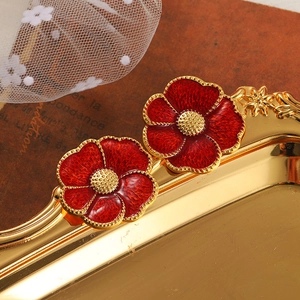 Detail of red enamel flower earrings with gold trim on vintage textured background