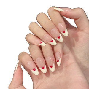 French tip almond press-on nails in nude pink with a small red heart and cream white edge