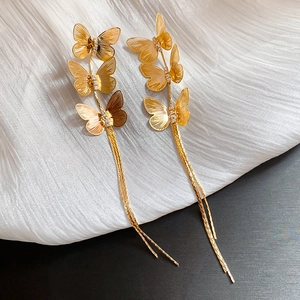 Detailed view of gold butterfly earrings with sparkling rhinestones and long tassels