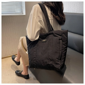 Detail showing the textured waterproof nylon fabric and wide shoulder strap of the black tote