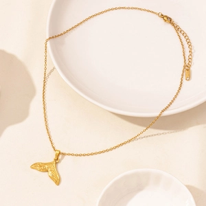 Macro view of whale tail pendant with vintage texture on adjustable gold stainless steel chain
