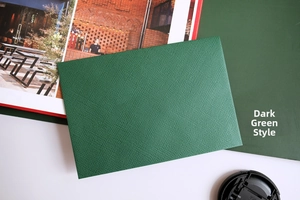Vista macro di una busta verde scuro con trama a lino incrociata di alta qualità e finitura