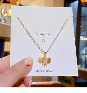 Golden elephant pendant necklace with rhinestones displayed on a white thank you card