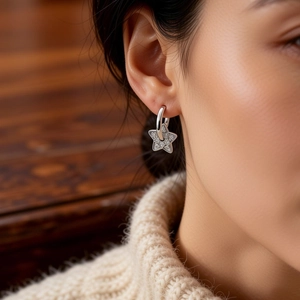 Macro detail of silver star drop earrings with pavé cubic zirconia worn by model
