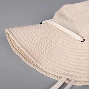 Detailed view of beige sun hat with reinforced brim stitching and adjustable drawcord