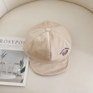 Dettaglio del ricamo a orsetto e trama in velluto a coste su questo cappellino da neonato