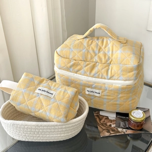 Close-up of quilted yellow and blue checkered makeup bags with stylish top handle design