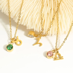 Gold zodiac bracelets with colorful birthstones on white decorative coral display