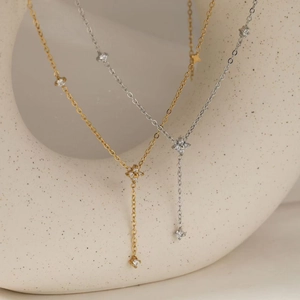 Elegant gold and silver Y-shaped necklaces with clover zirconia pendants on ceramic