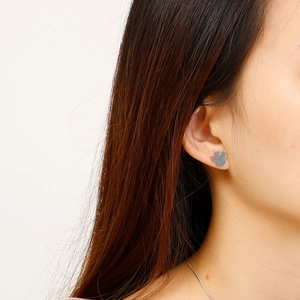 Close-up of a silver four-leaf clover stud earring worn on a model earlobe