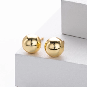 Macro shot of polished gold-plated S925 sterling silver ball stud earrings on a white pedestal