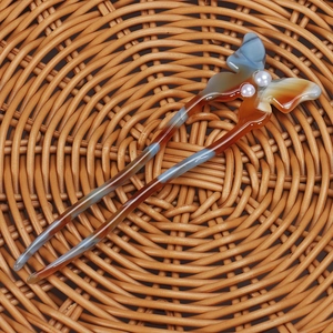 Detail of a butterfly agate hair pin with pearls on a woven rattan texture background