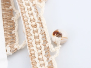 Detail shot of beige hand-woven fabric with shell beads on a bohemian maxi dress