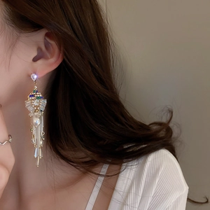 Close-up of dangling fringe earrings with colorful zircon and pearls on a model