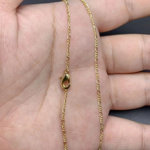 18K gold plated Figaro chain necklace with lobster clasp shown on a palm for scale
