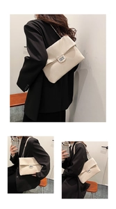 Detail showing the pleated texture, silver chain strap and metal lock of the cream shoulder bag