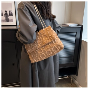 Chic beige crossbody bag with fringe texture and gold chain strap on model's shoulder