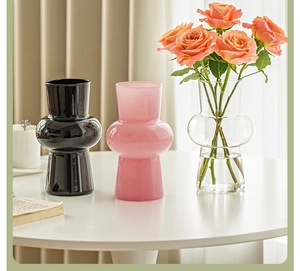 Three elegant gourd-shaped glass vases in black, pink, and clear colors on a white table