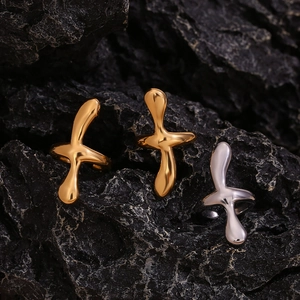 Detailed shot of irregular lava style cross rings in gold and silver on black rock