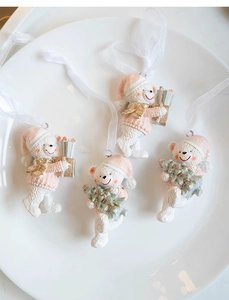 Detail view of four resin Christmas bear ornaments with pink sweaters and gold glitter