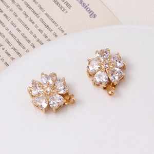 Detailed view of gold five-petal flower clasps with heart-shaped zircon on white porcelain