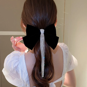 Detail showing elegant black velvet bow hair clip with shimmering long diamond tassels