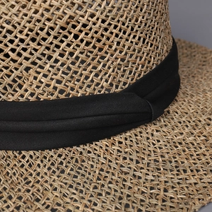 Close-up of handwoven straw sun hat with fine cross-weave texture and black ribbon detail