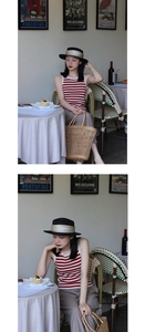 Detail of a chic black ribbon straw boater hat paired with a red striped vest in a cafe
