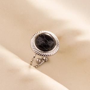 Macro shot of silver stainless steel ring with black cracked gemstone on silk