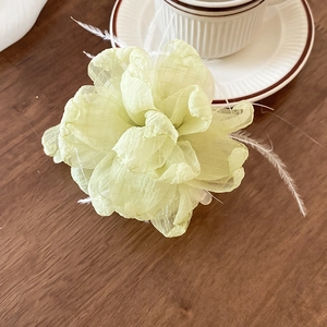 Nahaufnahme der hellgrünen Organza-Blüten-Haarklammer auf einem rustikalen Holztisch