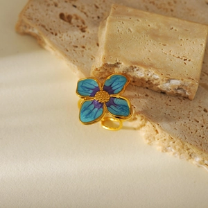 Detailed close-up of blue and purple enamel flower ring on natural stones