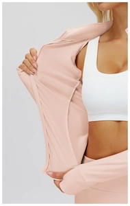 Détail du sweat de sport rose avec fermeture éclair, texture du tissu et brassière blanche