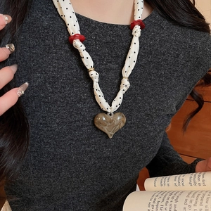 Close-up of heart pendant necklace with polka dot fabric chain and amber acrylic charm