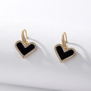 Detailed close-up of heart-shaped earrings with black enamel and zircon pavé settings