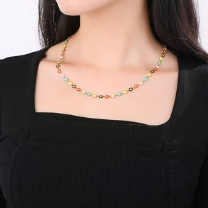 Close-up of a model wearing a gold titanium necklace with colorful daisy flower charms
