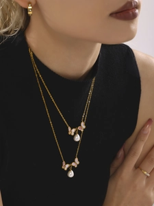 Détail d'un collier papillon en or 18 carats avec perle sur un mannequin en haut noir